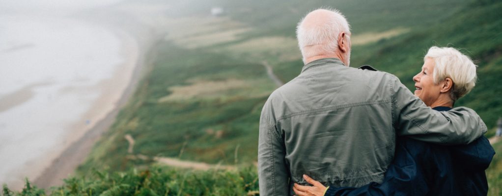 Older couple embracing each other overlooking the ocean