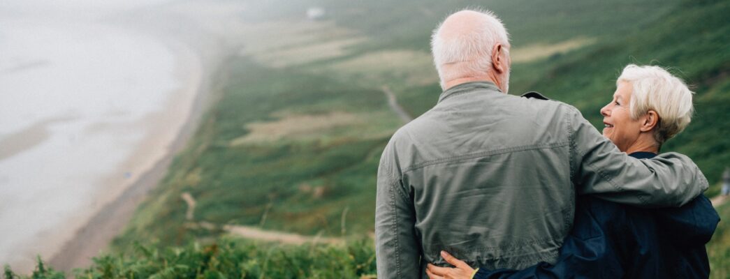 Older couple embracing each other overlooking the ocean