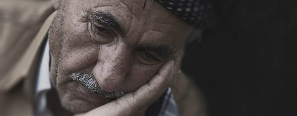 An elderly man with his head in his hand looking disappointed