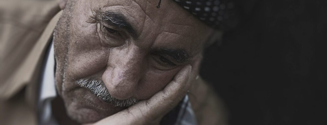 An elderly man with his head in his hand looking disappointed