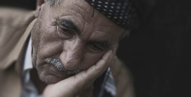 An elderly man with his head in his hand looking disappointed