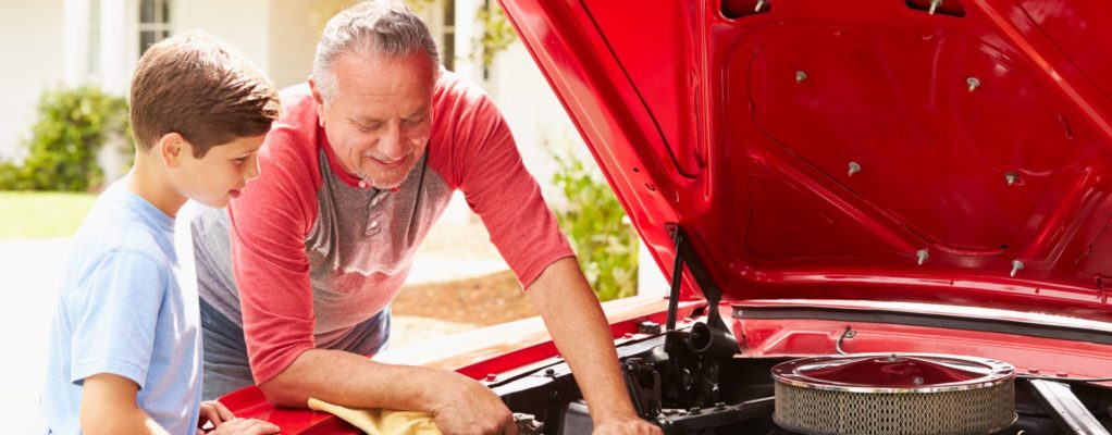 Grandfather and grandson work on a car