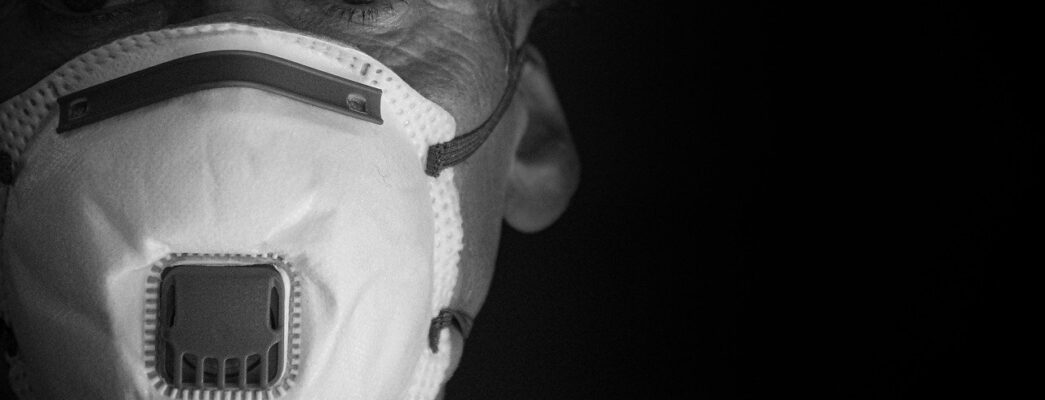 An elderly man wears a face mask