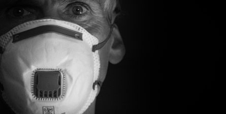 An elderly man wears a face mask