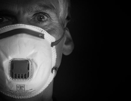An elderly man wears a face mask
