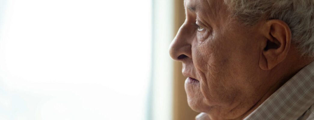 an old man stares out a window