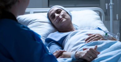 a woman lies in a hospital bed while receiving cancer treatment
