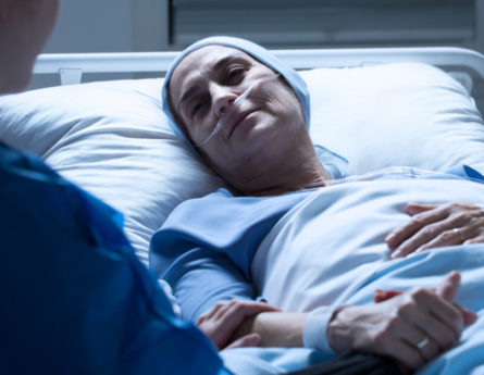 a woman lies in a hospital bed while receiving cancer treatment