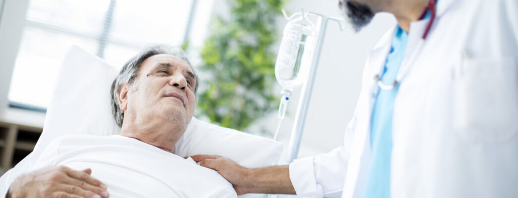 a man in a hospital bed talks to a doctor