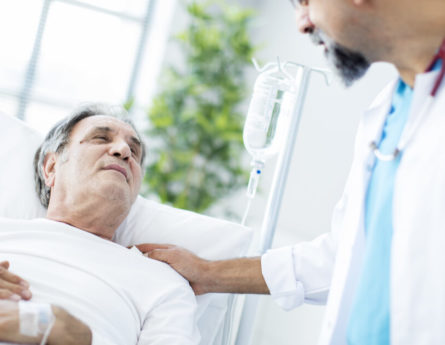 a man in a hospital bed talks to a doctor