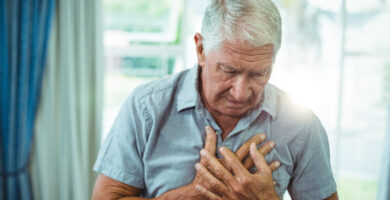 an older man holds his chest in pain
