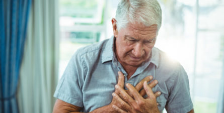 an older man holds his chest in pain