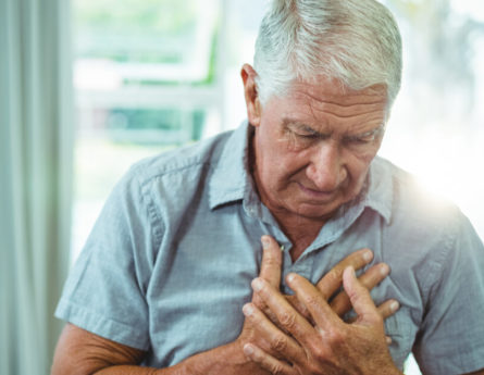 an older man holds his chest in pain