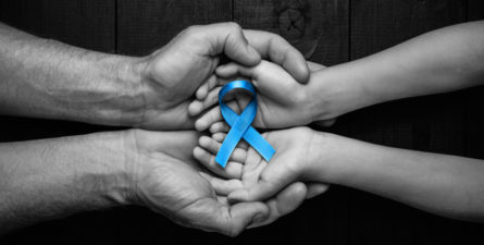 Two sets of hands holding a blue ribbon