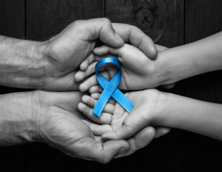 Two sets of hands holding a blue ribbon