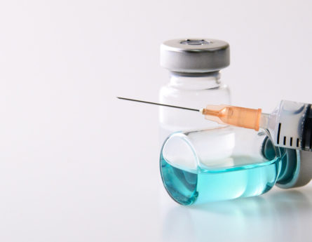 a needle resting on a bottle of fluid