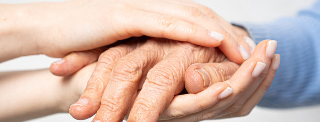 a younger person holds the hands of an older person