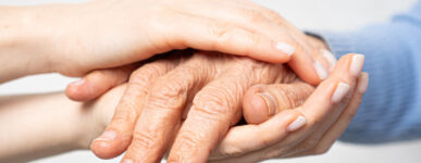 a younger person holds the hands of an older person
