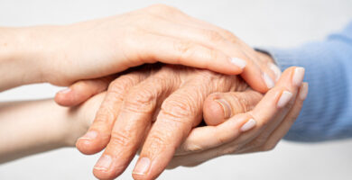 a younger person holds the hands of an older person