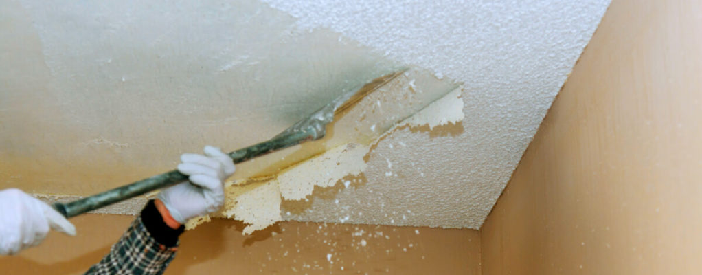 industrial worker removing popcorn ceiling with asbestos