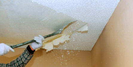 industrial worker removing popcorn ceiling with asbestos