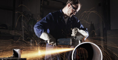 industrial worker in a workshop with sparks and dust in the air around him