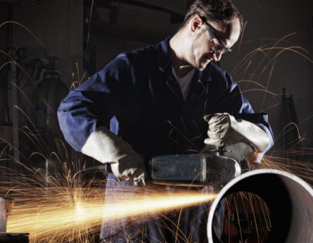 industrial worker in a workshop with sparks and dust in the air around him