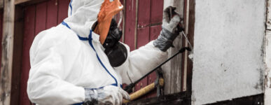 Man in hazmat suit working on home