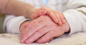 A person comforts a loved one by placing their hand on top of their loved one's hand
