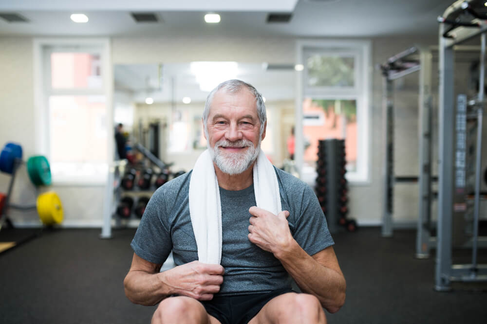 Elderly man in gym with towel around his neck