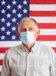 Man in mask standing in front of American flag