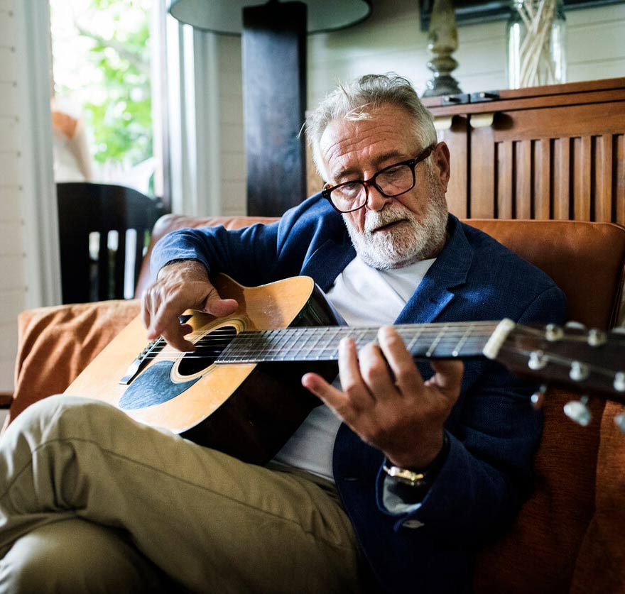 Older man in glasses playing the guitar