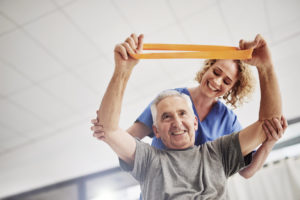Nursing helping an elderly man in physical therapy
