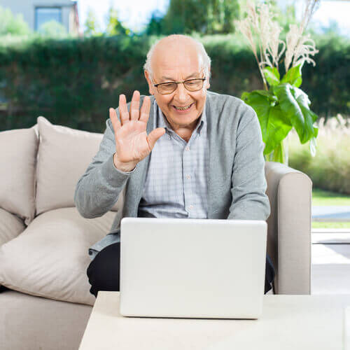 Elderly man on a video call on his laptop waving