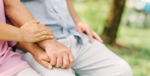 Two people sit holding hands