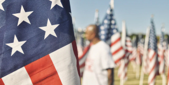 Man standing in field with american flags