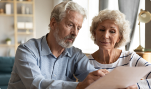 An elderly couple reviews a list of bankrupt asbestos defendants