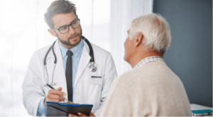 An elderly male patient discusses mesothelioma symptoms with his doctor