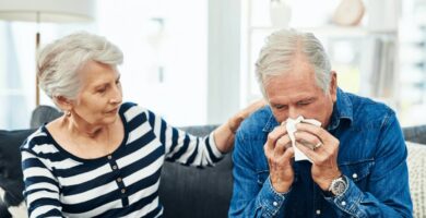 Man blowing his nose whole woman comforts him