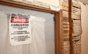 Asbestos danger sign posted on the door of a dilapidated structure