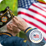 Veteran saluting next to an American flag