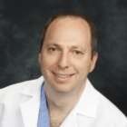 Headshot of Dr. Martin Goodman in a white lab coat and a blue shirt.