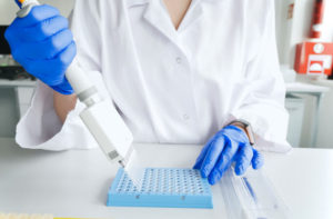 Research technician with multipipette in genetic laboratory