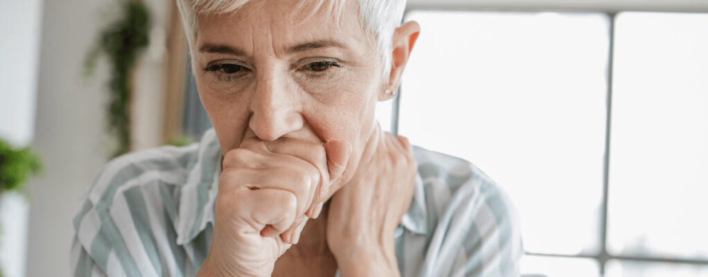 Woman coughs into hand