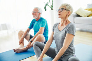 An older woman and man seated on yoga mats