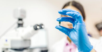 A scientist holding a pill