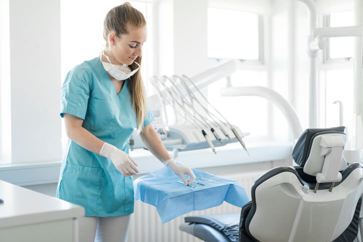 Young woman dentist prepares her tools on a blue dental tray