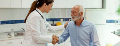 A doctor shakes a male patient's hand and pats him on the shoulder with her other hand