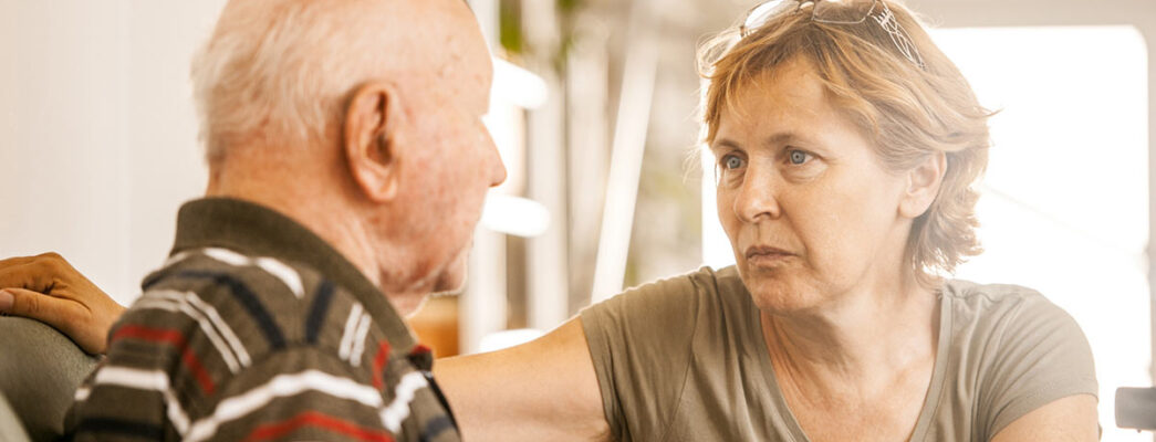A woman who appears to be around 40-50 is looking intensely at a much older man who may be her father.