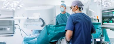 Doctors in blue scrubs work on a patient in an operating room